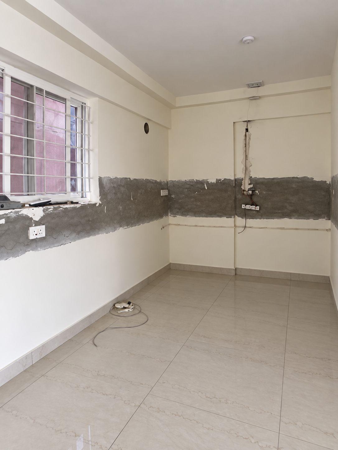 Kitchen before interior work — bare walls, exposed plumbing and loose wiring