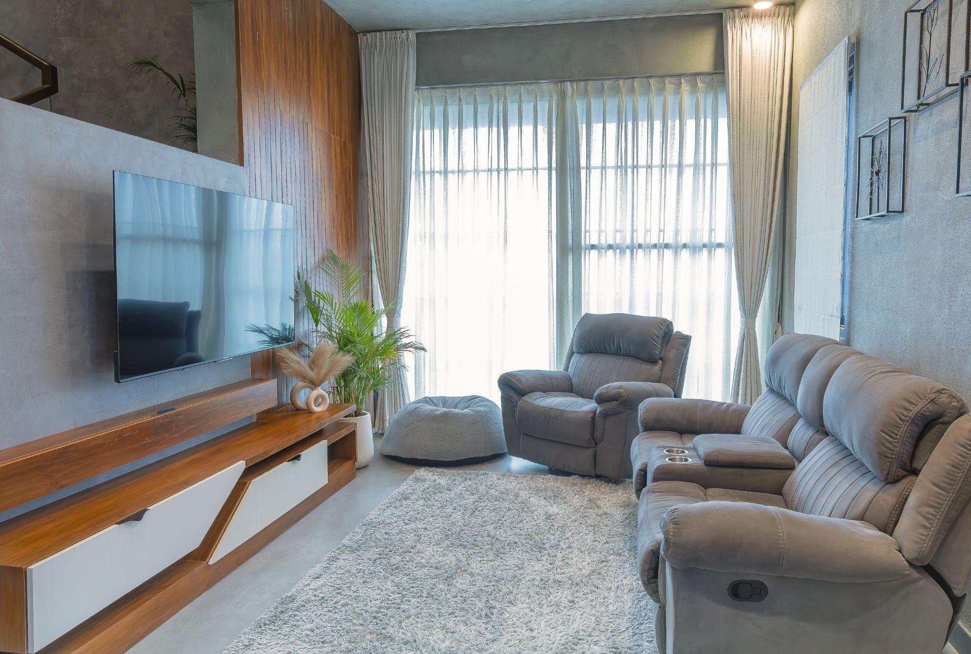 Gubbi Gudu villa, Anjanapura, Bangalore — living room with a floating walnut TV unit, angled white drawer fronts and a full-height fluted wood wall panel