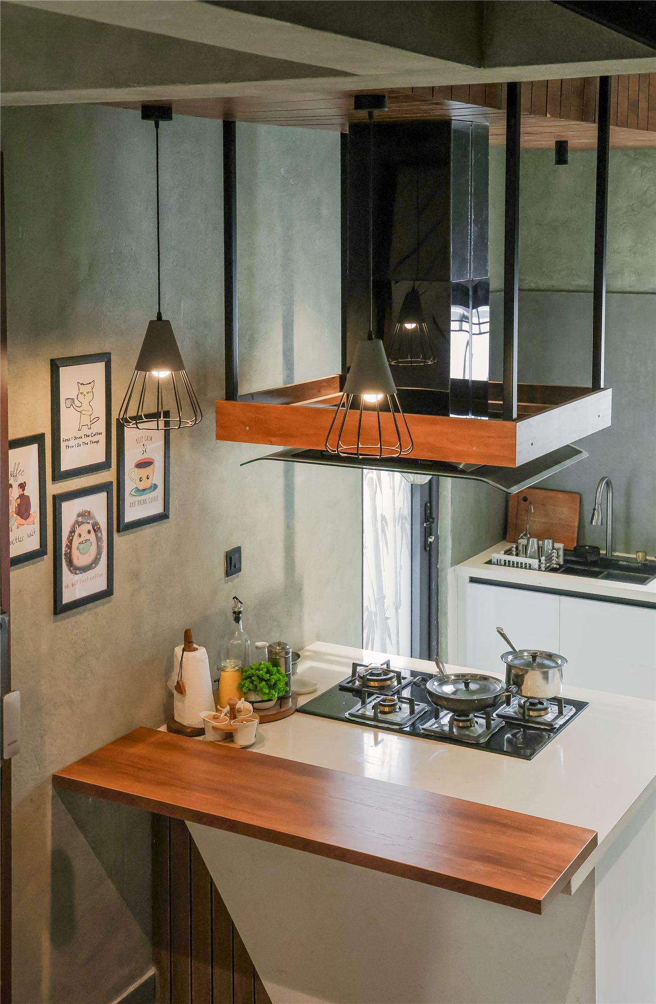 Gubbi Gudu villa, Anjanapura, Bangalore — island kitchen with a suspended chimney clad in wood and a wooden breakfast counter, no loft