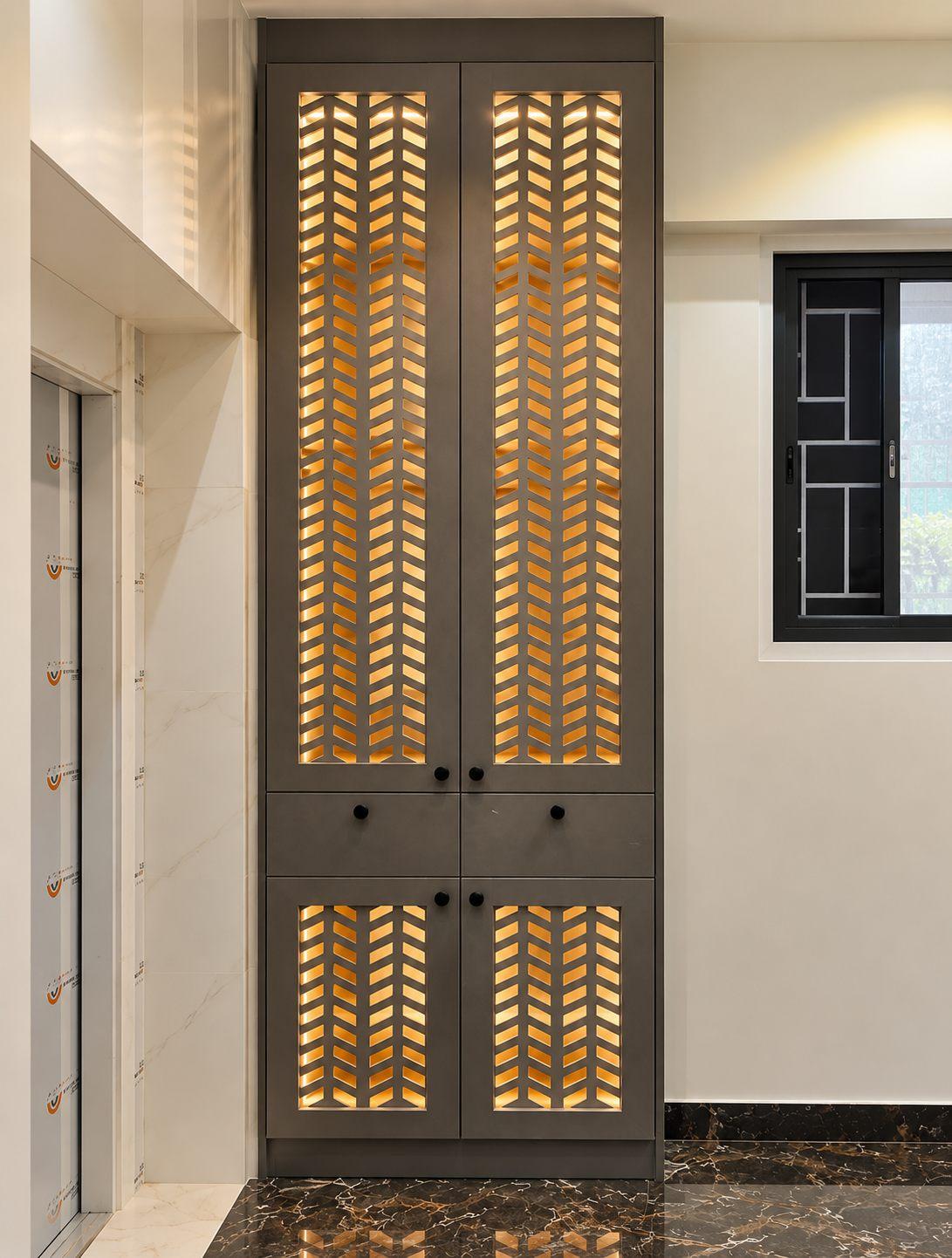 Gubbi Gudu villa, Anjanapura, Bangalore — tall shoe cabinet with backlit jaali shutters by the staircase