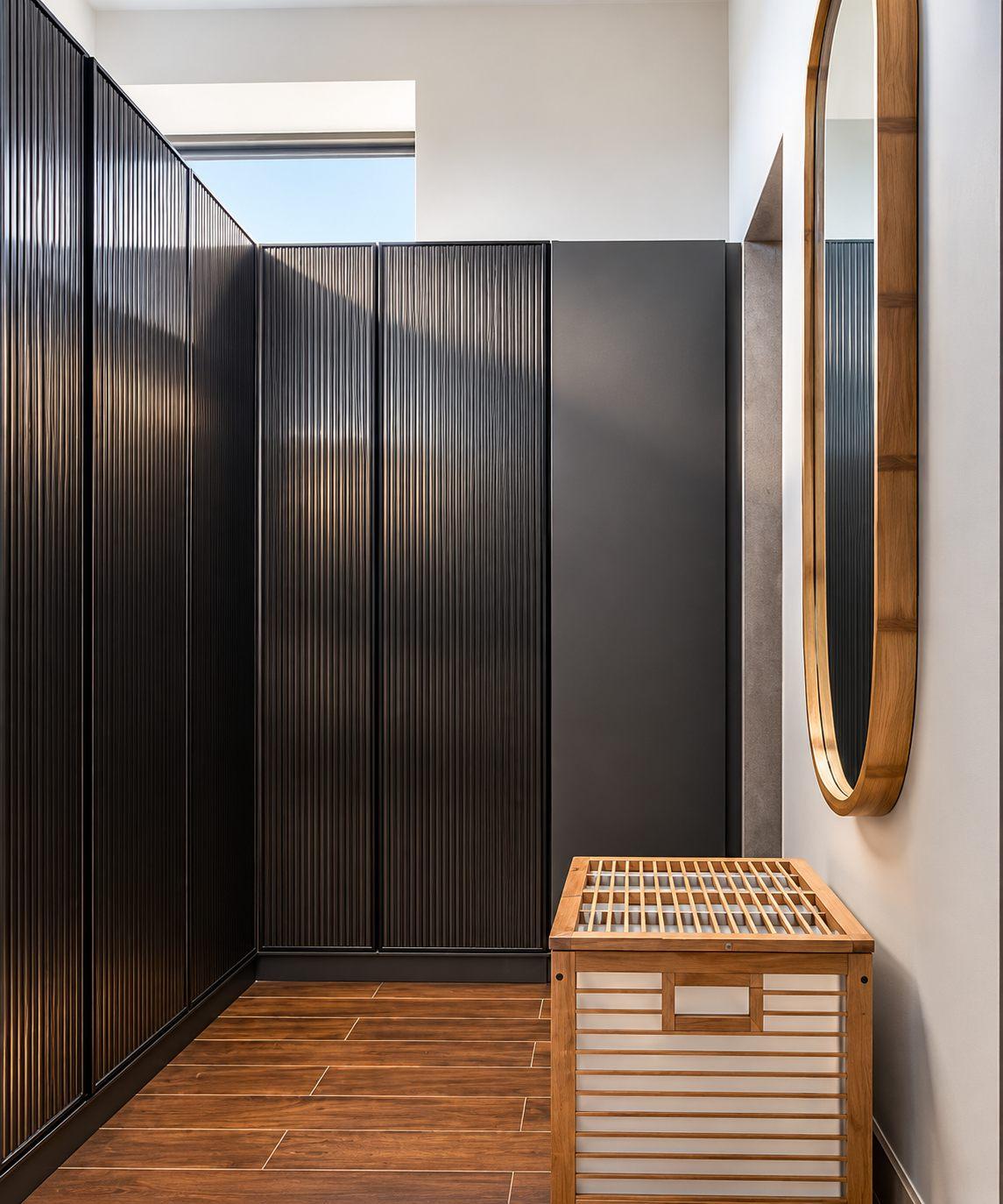 Gubbi Gudu villa, Anjanapura, Bangalore — walk-in closet with dark wardrobes and an oval mirror