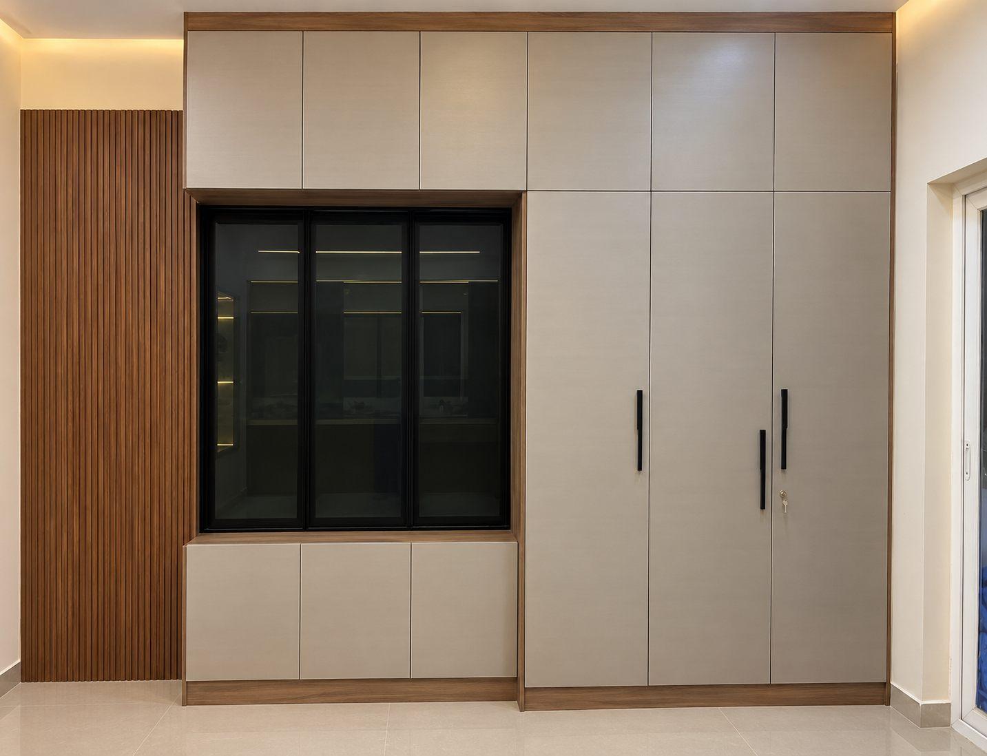 Master bedroom wardrobe in beige laminate with a black-framed glass centre unit, lofts and a fluted wood side panel
