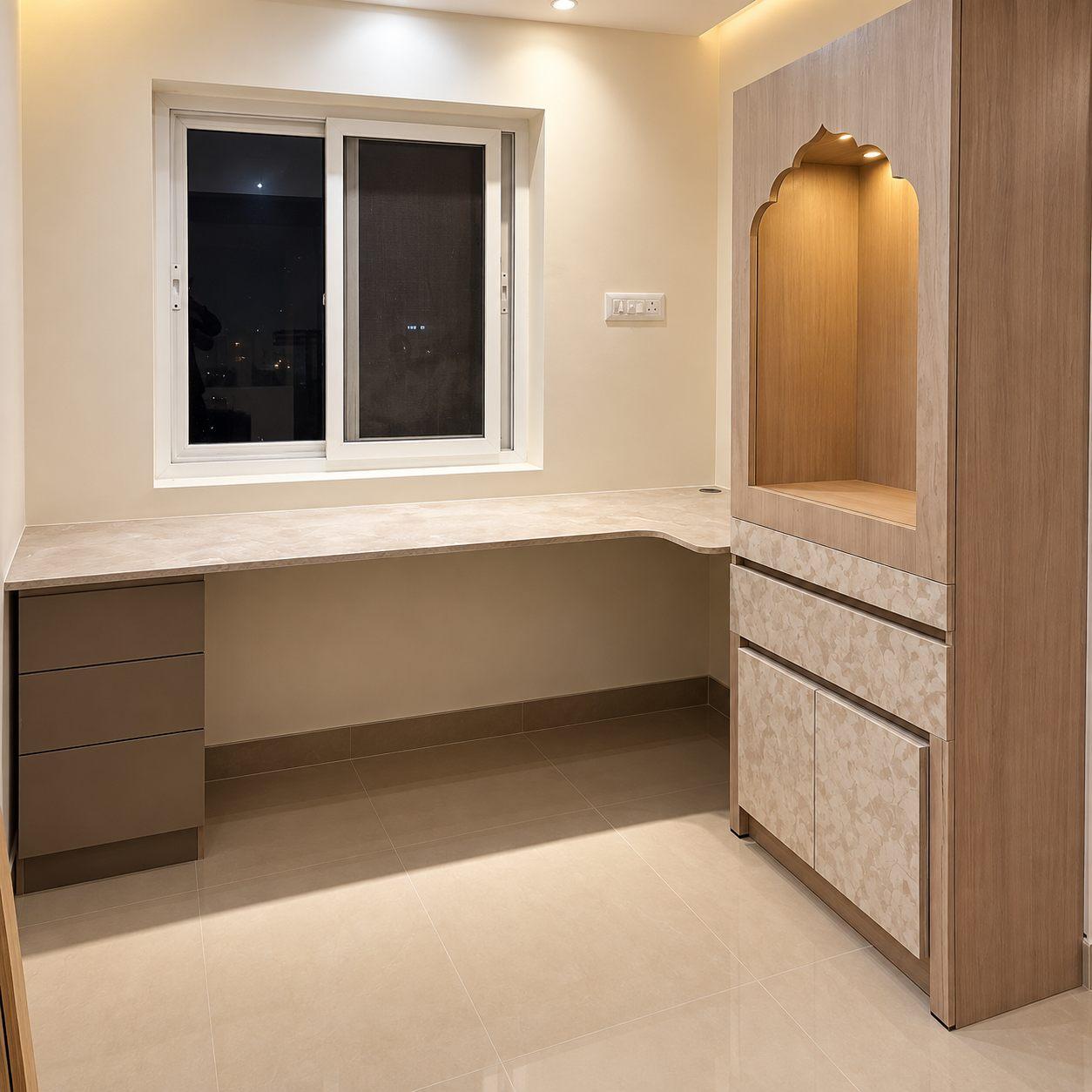 L-shaped study table under a window with a tall pooja unit featuring an arched niche and floral laminate drawers