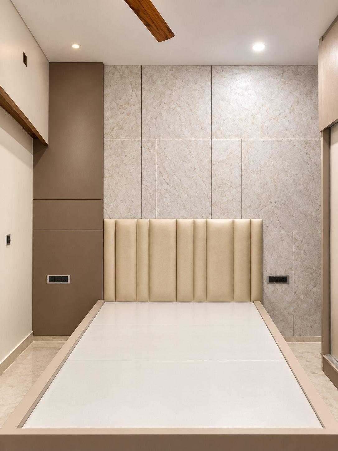 Parents’ bedroom with a stone-finish wall panel and upholstered headboard — Saral Mane, a G+2 house on Kanakapura Road, Bangalore