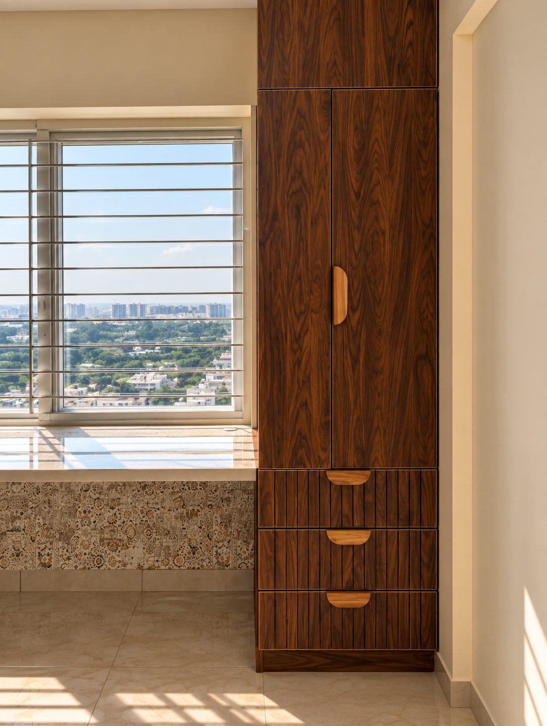 Tall walnut storage unit with fluted drawers beside a window with a patterned sill