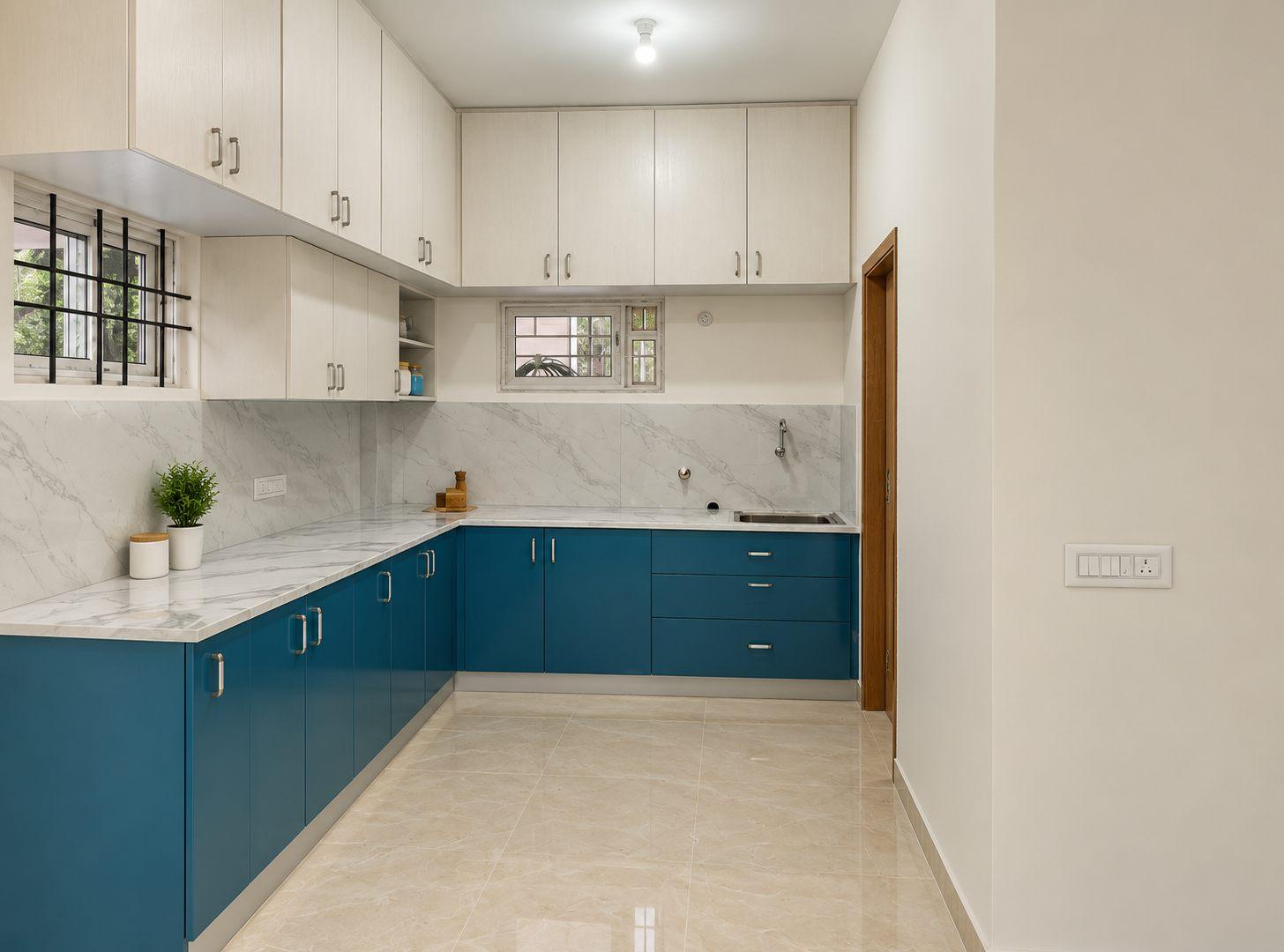 Rental-floor kitchen in The Green Storey, Bannerghatta — dark blue base cabinets, white lofts and a marble-look counter